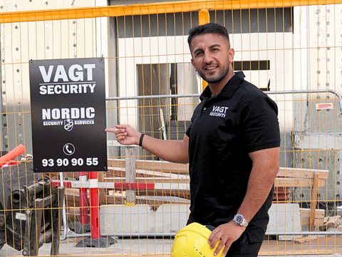 Rahmi Secilmis, indehaver af Nordic Security, peger på et Nordic Security-skilt på en byggeplads