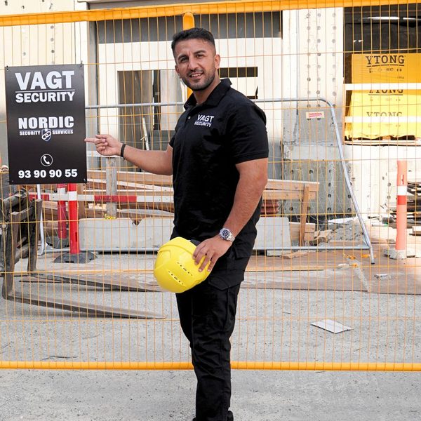 Rahmi Secilmis, indehaver af Nordic Security, peger på et Nordic Security-skilt på en byggeplads